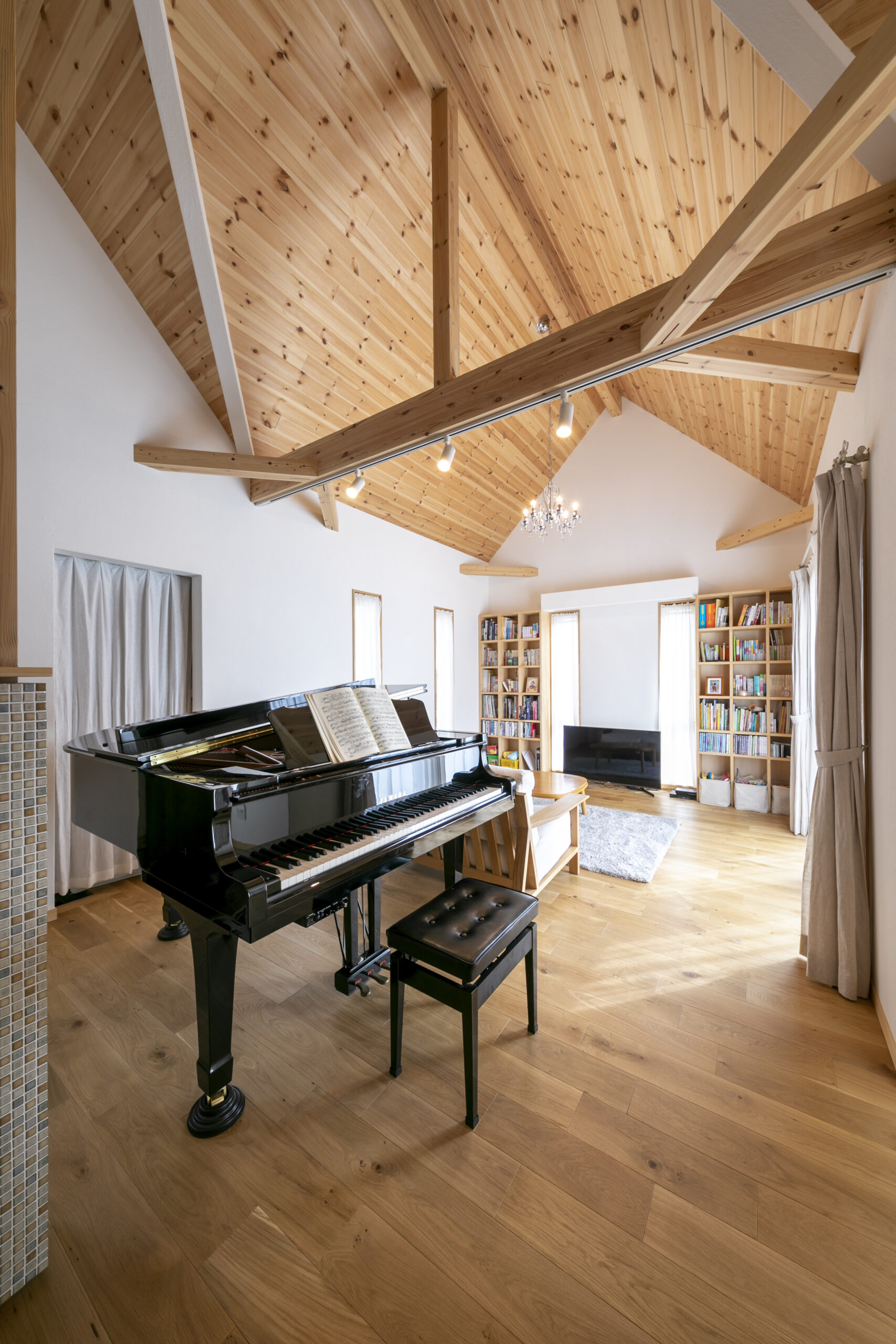 リビングにはグランドピアノと大きな本棚を設置。床はオーク、天井はレッドウッドの無垢材を使用
