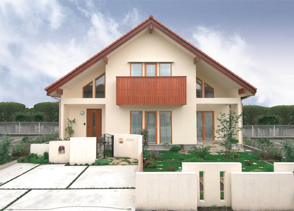 木製サッシと木製バルコニーがほんのり色のついた漆喰と調和した美しい外観。塀も漆喰で仕上げました